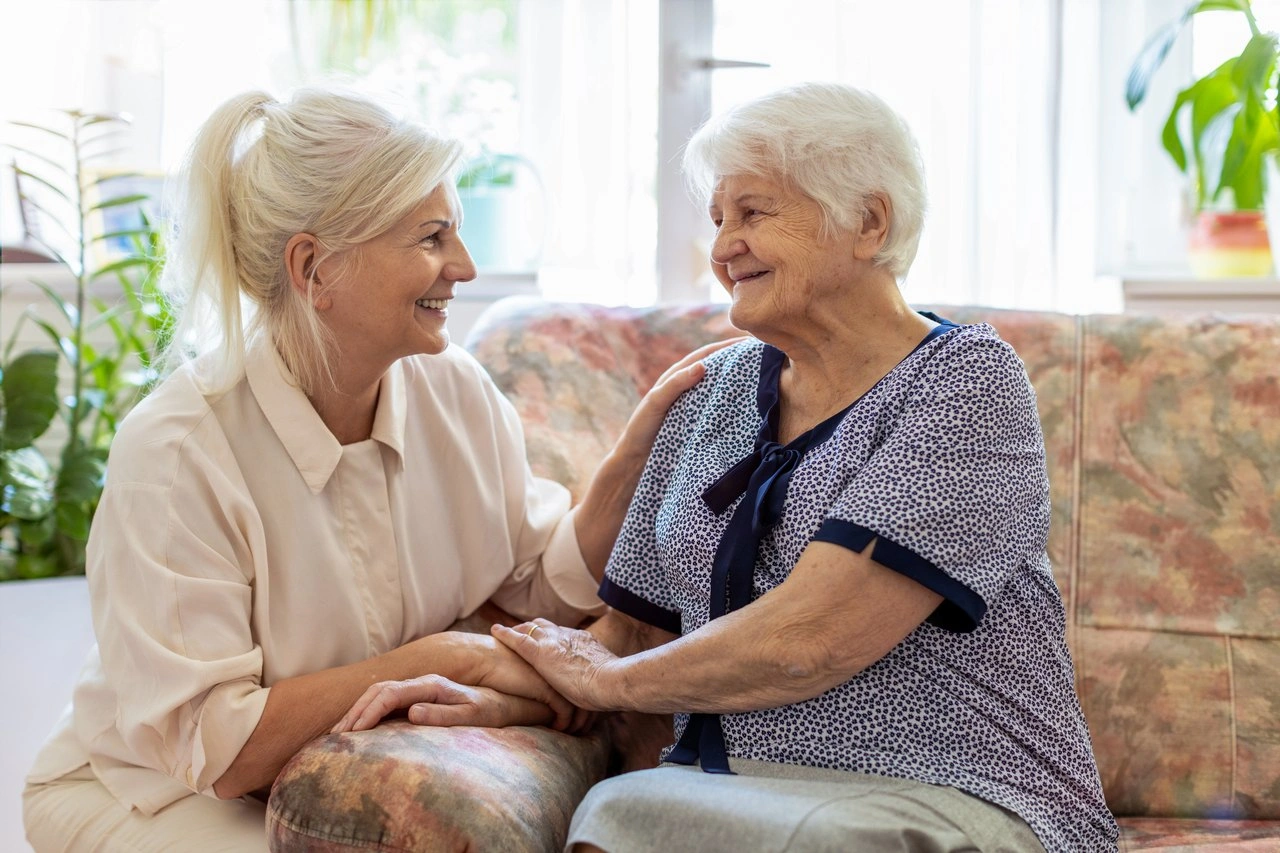 Betreuungskraft hilft einer Seniorin beim Gehen in ihrer Wohnung