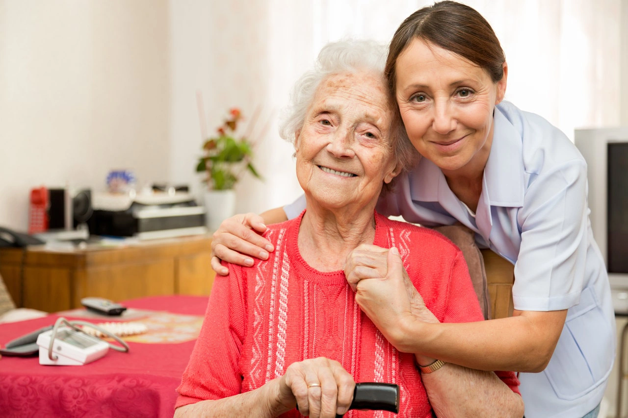 Betreuungskraft und Seniorin sitzen gemeinsam am Küchentisch